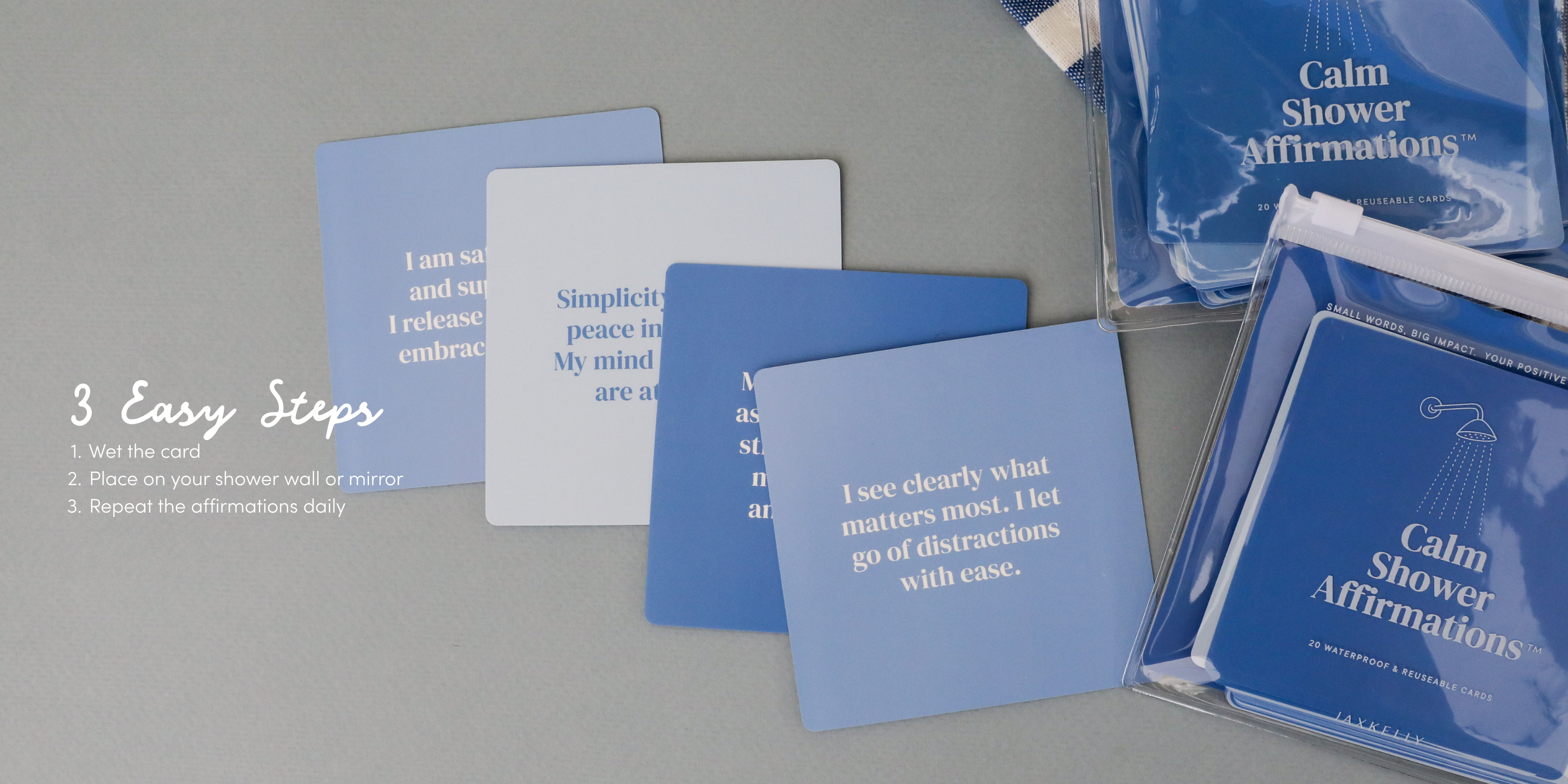 A set of blue affirmation cards, titled Calm Shower Affirmations, is arranged on a gray surface, with three easy steps for use listed on the left in white text.