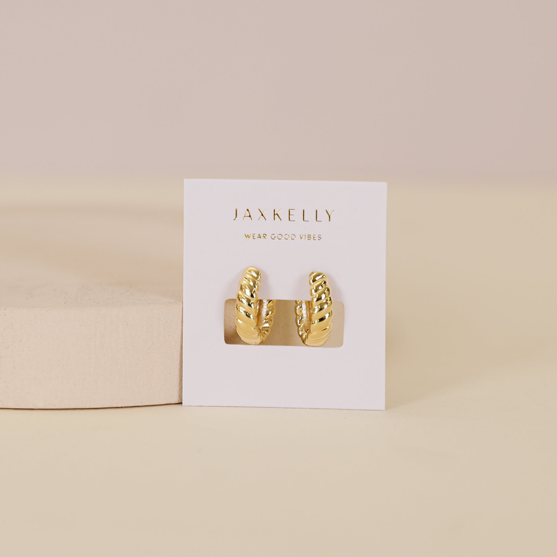 The Small Channel Gold Hoop earrings feature 18K gold plating and sterling silver posts, displayed on a “JaxKelly Wear Good Vibes” card against a pale, neutral background.