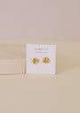 The Petite Gold Knot Earrings feature 18K gold plating and come displayed on a white JaxKelly card with the "Wear Good Vibes" message—perfect for everyday wear and presented against a soft beige background.