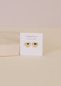 The Puffed Gold Heart Earrings, featuring shiny 18K gold plating and a puffed heart design, are shown on a white JaxKelly card against a soft beige background.
