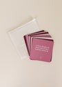 A set of maroon Boundaries Shower Affirmations™ cards, waterproof and fanned out on a light surface, features one card reading, "I release all guilt and shame that setting a boundary brings up," beside a translucent pouch.