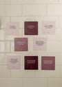 Boundaries Shower Affirmations™ features eight square waterproof cards in pink and purple tones, each with a unique motivational message about setting boundaries and self-care, arranged on a white tiled wall.
