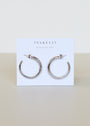 The Silver Everyday Hoop - Medium, crafted from sterling silver, is displayed on a white card featuring the JaxKelly logo and "Wear Good Vibes" in gold, making it an ideal choice for fans of classic jewelry.