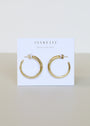 A pair of Gold Everyday Hoop - Medium earrings displayed on a white card featuring the JAX KELLY brand and Wear Good Vibes slogan, highlighting these timeless jewelry essentials.