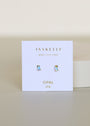 A pair of Teardrop Stud - Fire Opal earrings shown on a white card with gold "JAXKELLY Wear Good Vibes" and "OPAL joy" text, set against a light, neutral background.