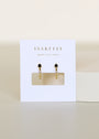 The Open Mini Hoop Earring - Black features gold-plated hoops with small black CZ stones, displayed on a white JaxKelly card that says WEAR GOOD VIBES in gold, set against a minimal cream background.