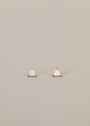 The White Opal Mini Energy Gems - Joy are small triangular stud earrings featuring iridescent lab-grown white opal stones set in 18k gold plating, shown on a plain beige background.