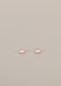 The White Opal Double Stud Stack features small rectangular white opal stones set in 18k gold plating, each accented with a tiny round lab-grown clear gemstone, displayed on a simple light beige background.