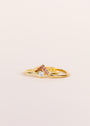 The Pink Lambda Ring features a central round white gemstone on an 18k gold-plated band with Lambda v-shaped accents set with small pink cubic zirconia, shown against a plain light background.