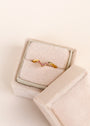 The Pink Lambda Ring features a v-shaped chevron design with sparkling pink cubic zirconia, displayed in an open, light beige velvet ring box.