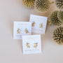 Three pairs of Sun Ray - Mother of Pearl gold plated earrings with sterling silver posts rest on white calming cards, displayed on a light surface and accented by beige thistle flowers.