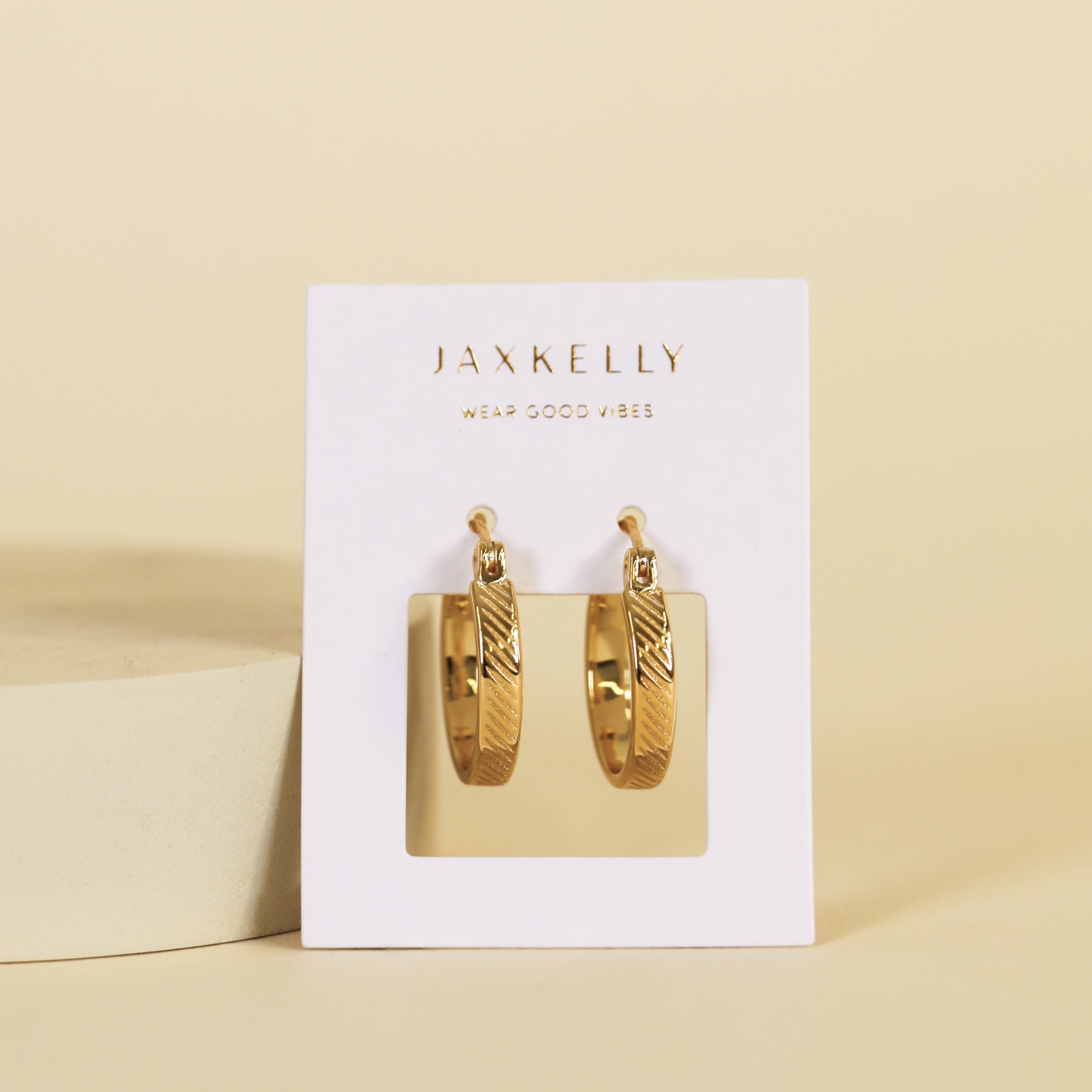 Textured Hoop - Earring with 18k gold plating, shown on a white JaxKelly card featuring "Wear Good Vibes" below the brand name, set against a light beige background.