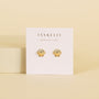 A pair of hypoallergenic Seashell Stud earrings in gold, shaped like shells, are displayed on a white JaxKelly card with the brand slogan “Wear Good Vibes” printed above the earrings.
