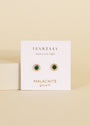 The Malachite Sun Stud features vibrant malachite stones and 18k gold plating on a white JaxKelly "Wear Good Vibes—Malachite Growth" card, displayed against a beige background.