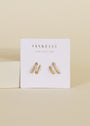 A pair of Pave Spiral - Earrings with small pave stones, displayed on a white card labeled JaxKelly and Wear Good Vibes, set against a neutral beige background.