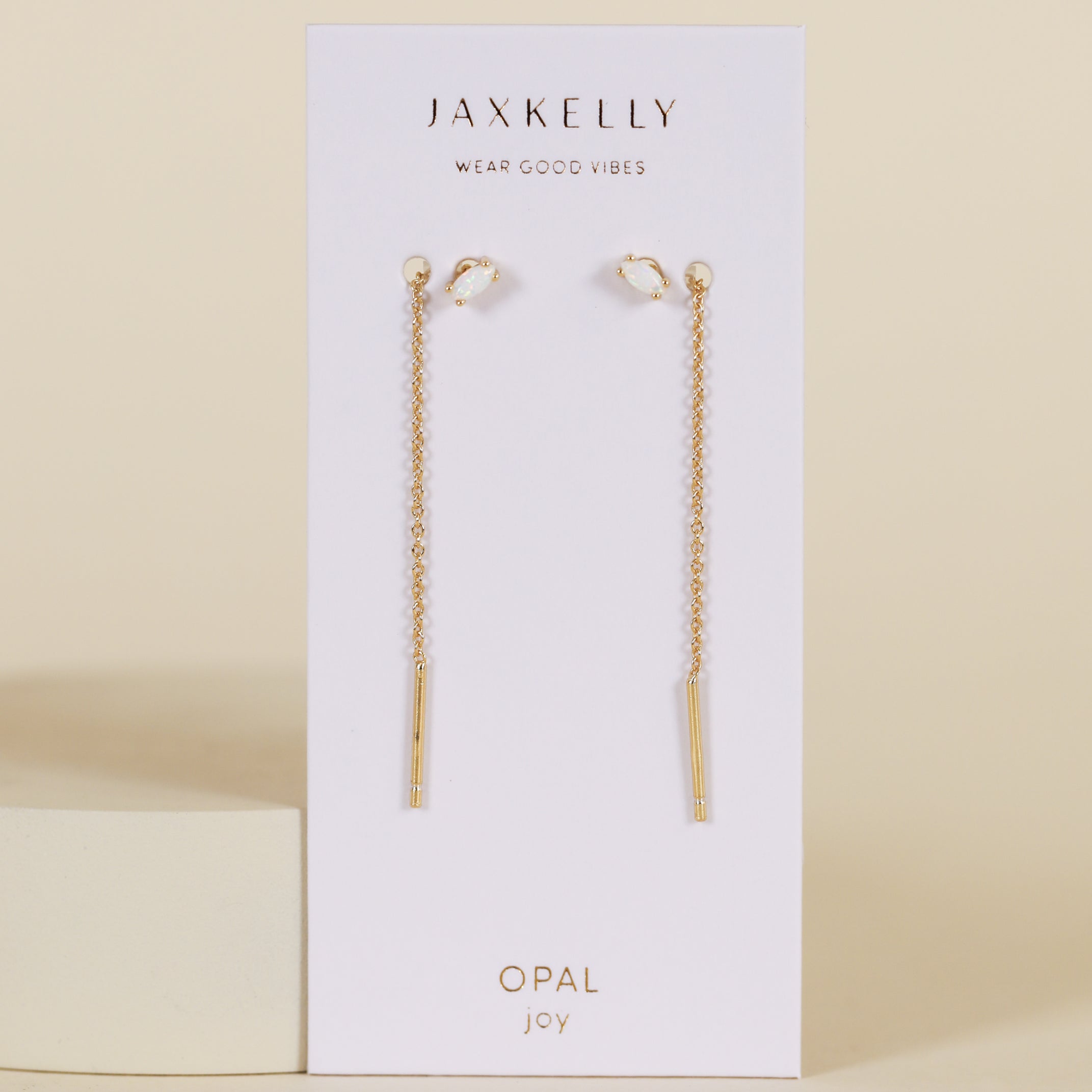 JaxKelly’s Studded Threader - White Opal earrings, displayed on a branded card, feature 18K gold plated chains with slim bar pendants and opal accents, shown against a neutral background.