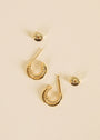 The Double Hoop - Earring features small, gold-plated hoops with a twisted design, shown alongside their round, faceted backs on a light beige background.