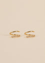 Pave Spiral - Earring: Gold ear cuffs with a minimalist spiral design, each adorned with a row of sparkling stones, displayed on a plain beige background.