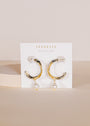 The Twisted Pearl Drop Hoop - Gold Earrings feature gold-plated twisted hoops with dangling freshwater pearls, shown on a white “JAX KELLY WEAR GOOD VIBES” card against a neutral background.