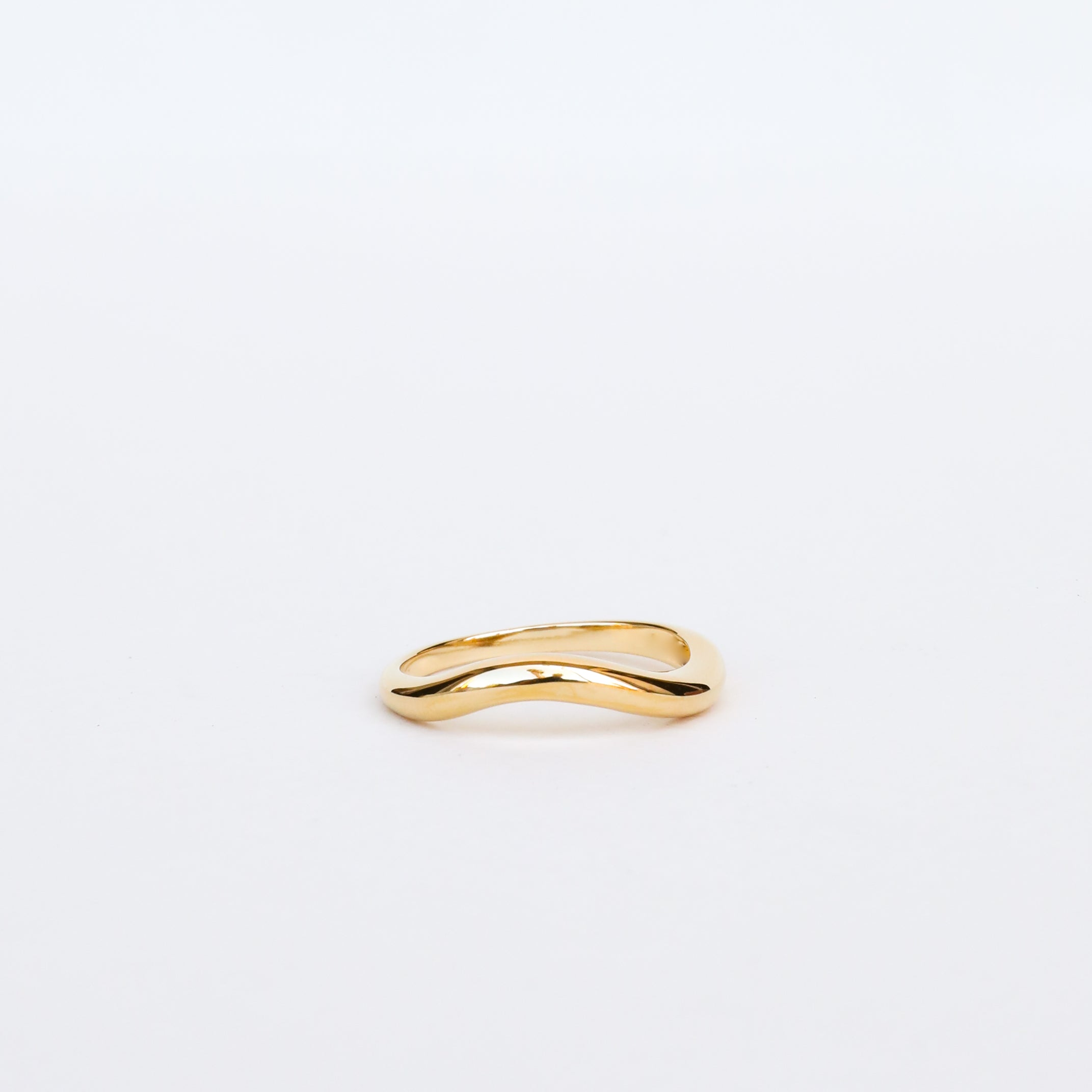 The Wave Ring, crafted in 18k gold with an elegant wave design, rests on a plain white background—an ideal choice for those who value timeless and lasting jewelry.