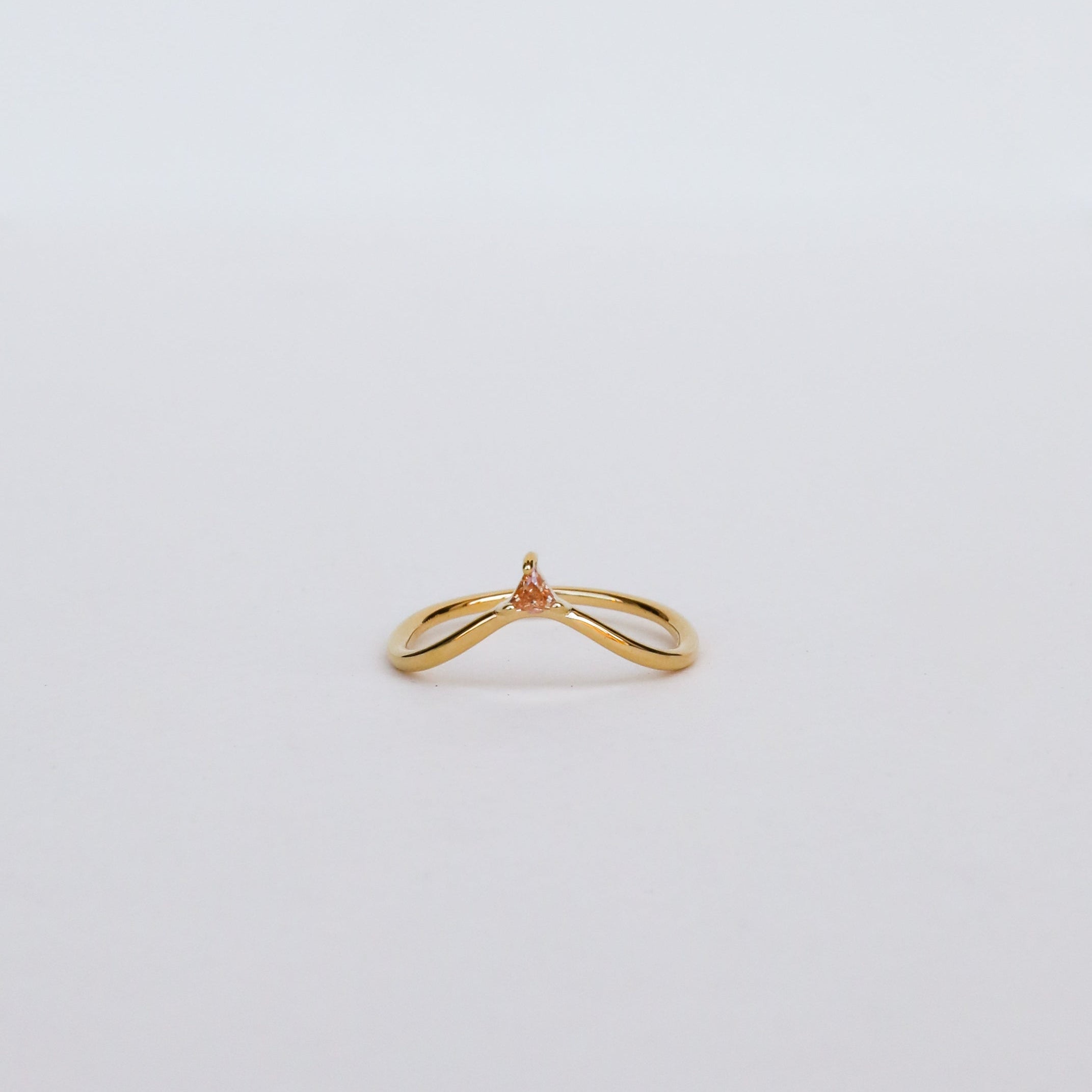 The Arched Triangle Ring - Champagne features a delicate 18k gold band with a small, champagne-colored pear-shaped gemstone at the center, set against a plain white background for an elegant, heirloom-inspired look.