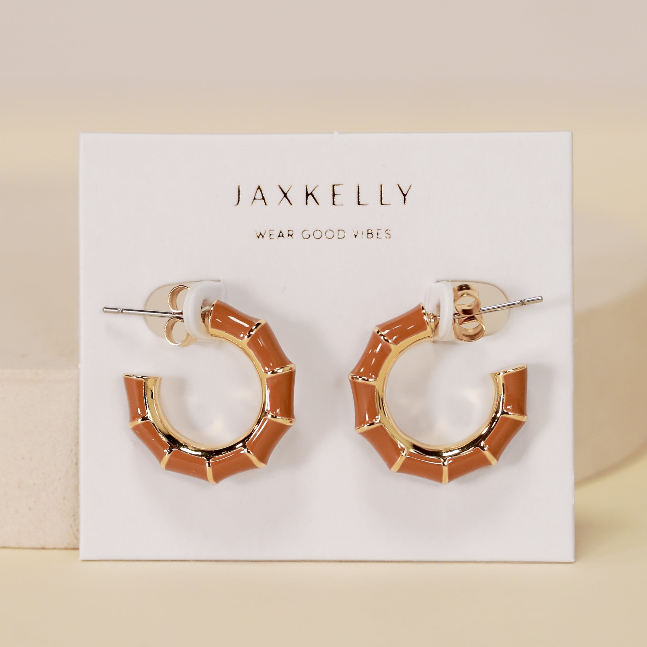 A pair of geometric, brown enamel Vintage Hoop Earrings with 18k gold plating displayed on a white JaxKelly card that says “Wear Good Vibes.”.