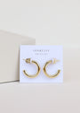 A pair of Gold Hoop - Smooth shiny gold plated earrings displayed on a white card labeled JaxKelly Wear Good Vibes, set against a simple, light background.