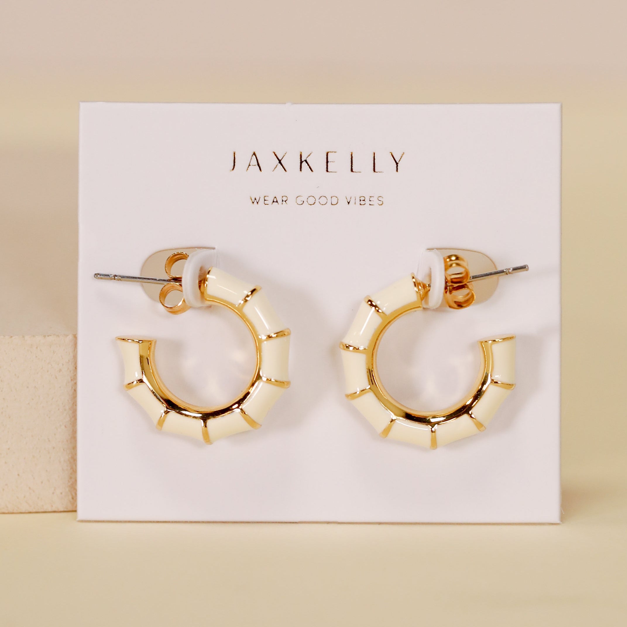 A pair of Vintage Hoop Earrings - Cream Enamel with a gold and cream segmented, geometric design is displayed on a white card featuring JAX KELLY and WEAR GOOD VIBES.