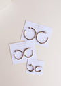 Three pairs of Silver Hoop - Smooth sterling silver earrings in varying sizes are displayed on white JaxKelly Wear Good Vibes cards, arranged on a light beige surface.