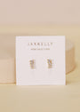 The Mini Crawler - White CZ - Gold Earrings are shown on a white card with "JaxKelly" and "Wear Good Vibes" in gold lettering, set against a soft beige background.