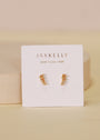 The Mini Crawler - Champagne CZ - Gold Earrings, featuring small gold plated studs with sparkling champagne CZ stones, are displayed on a JaxKelly Wear Good Vibes card against a soft beige, minimal background.