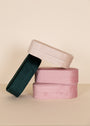 The JaxKelly Large Oval Velvet Jewelry Boxes in light pink are stacked against a beige background, serving as elegant travel organizers or stylish jewelry cases.