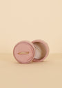 A delicate gold ring with small diamonds is shown in the open Circle Velvet Jewelry Box - Light Pink by JaxKelly, with the lid propped behind it against a soft beige background.