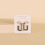 The Black Enamel Large Rectangle Hoop Earrings with sterling silver posts are showcased on a white JaxKelly card reading "Wear Good Vibes," set against a beige background.