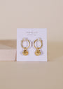 The Seashell Hoop Earring features gold-plated hoops with small gold seashell charms and sterling silver posts, displayed on a white JaxKelly card against a beige background.