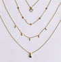 Four delicate gold necklaces by JaxKelly are arranged in a semi-circle. Discover the Mystery Necklace among heart, circles, bars, and blue triangle stone pendants—perfect for jewelry sales or as a surprise gift.