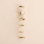 Six JaxKelly Mystery Rings, featuring unique designs like plain bands, pearls, stones, and decorative settings, are arranged vertically on a light beige background—perfect for a ring sale or as a surprise gift.