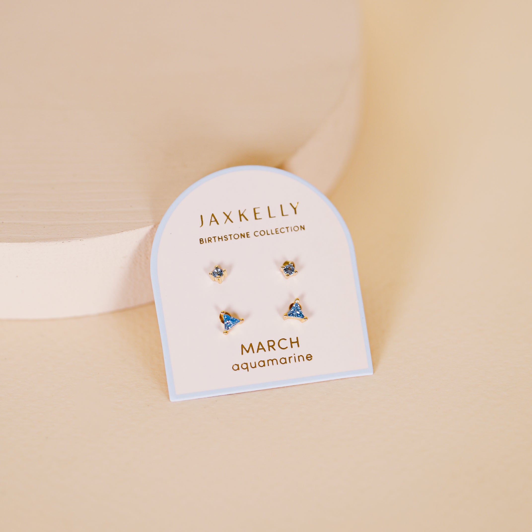 A card labeled "Birthstone Stud Earring Set - March" displays two pairs of small aquamarine sterling silver earrings against a beige background.