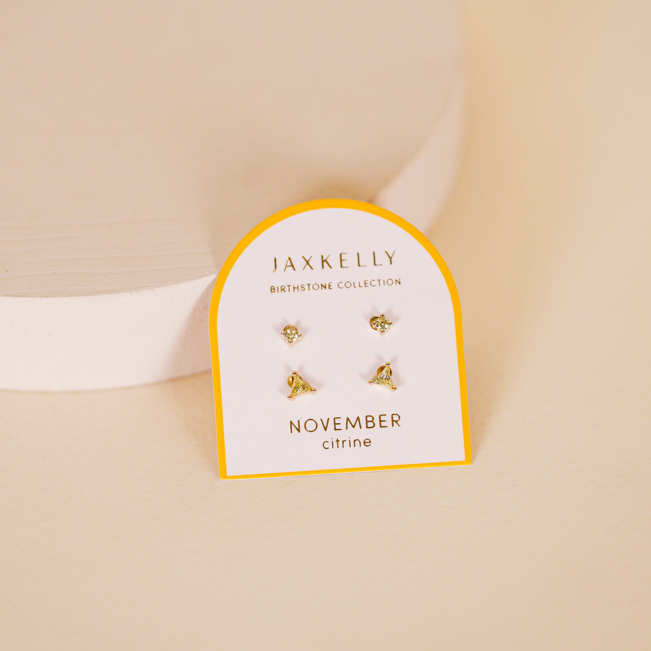 The Birthstone Stud Earring Set - November features small gold earrings with citrine gemstones, shown on a JaxKelly Birthstone Collection card labeled November against a soft beige background.