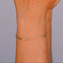A hand with brown painted nails is shown against a neutral background, adorned with three gold rings and the elegant Small Link Chain Bracelet on the wrist.