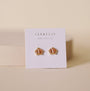 A pair of tarnish-free, 18K gold plated Champagne Baguette Crown Earrings by JaxKelly are shown on a white card labeled "Wear Good Vibes," against a neutral beige background.