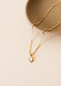 The Mother Of Pearl Gemstone Rectangular Pendant Necklace features an 18k gold plated chain, a small rectangular pendant with tiny decorative dots, and an adjustable clasp. Shown on a beige ceramic dish against a cream background.