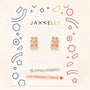 A pair of Ballet Slippers Enamel Flat Back Kids Earrings from JaxKelly, presented on a decorative card with colorful geometric designs and labeled hypoallergenic, feature kid-friendly posts perfect for sensitive ears—an ideal, stylish choice for any young dancer.