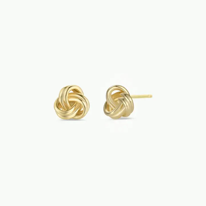 The JaxKelly Petite Gold Knot Earrings feature an intricate knot design with 18K gold plating. Displayed on a white background, one earring shows the front detail while the other highlights the post—ideal for everyday wear.