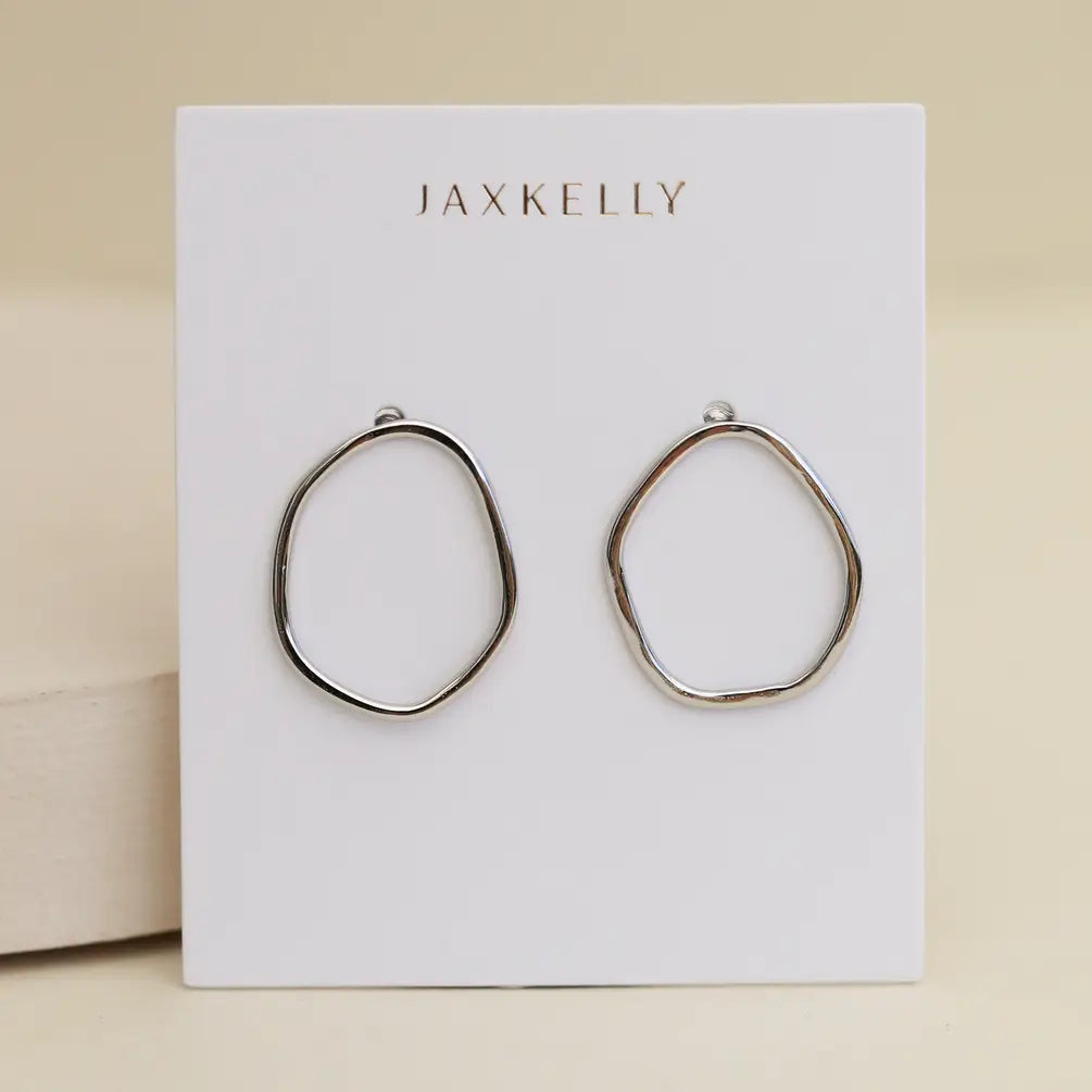 The Silver Organic Hoop by JaxKelly, crafted from sterling silver, is displayed on a white card with gold JaxKelly branding, set against a soft beige background.