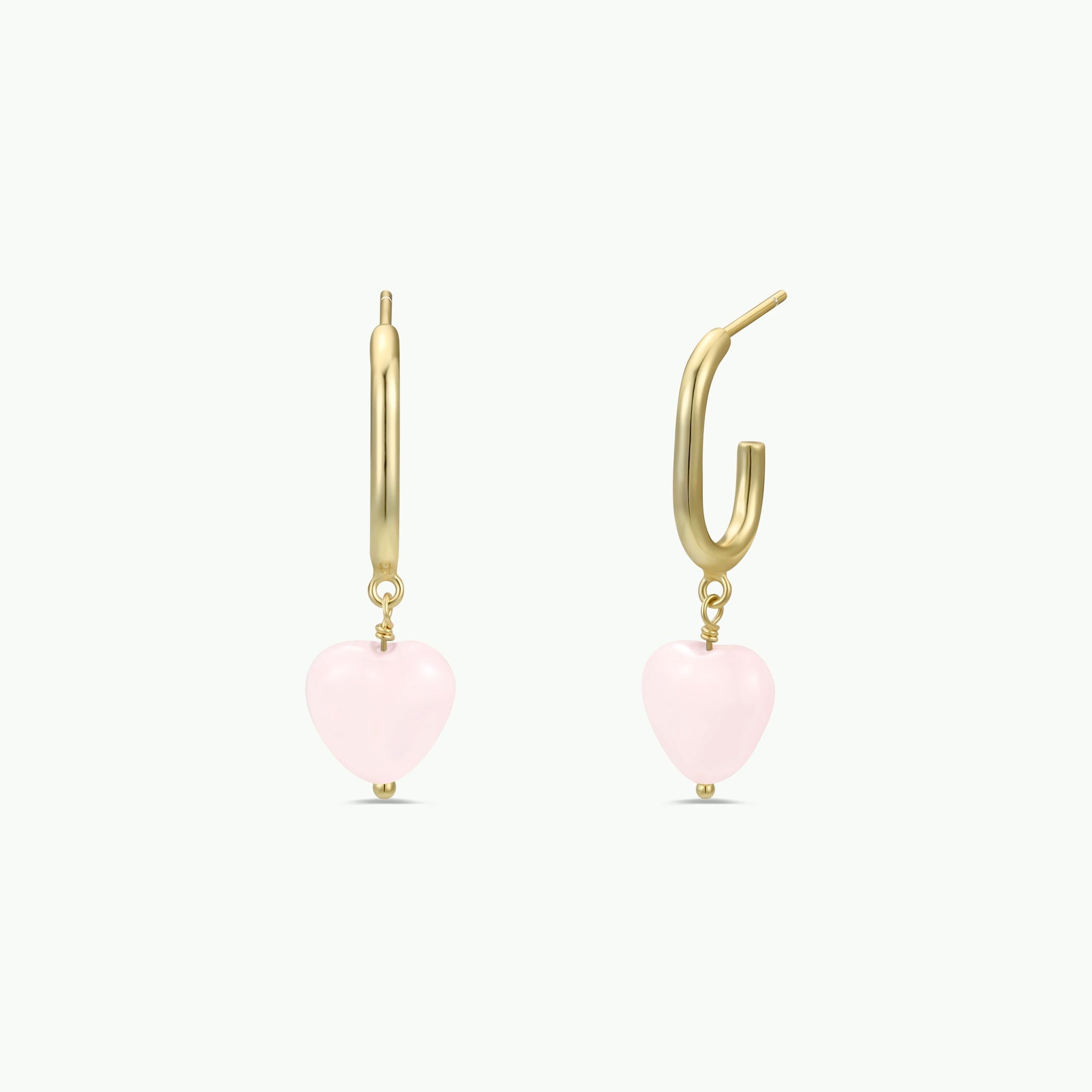 The Heart Drop - Rose Quartz earrings feature gold hoops with dangling rose quartz heart charms, displayed against a white background. These earrings are tarnish free for lasting shine.