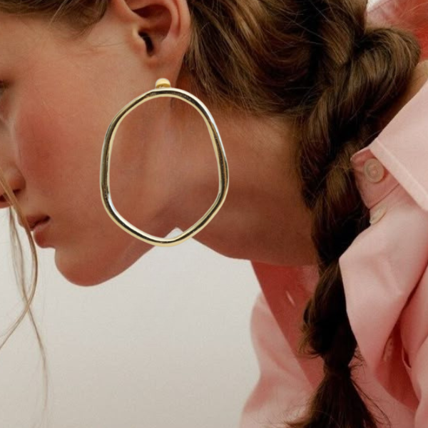 Model wearing large gold statement hoop earrings