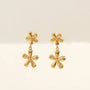 The JaxKelly Double Daisy Drop Earring features two gold-plated sterling silver floral elements—a small daisy on top and a larger, shiny daisy below—displayed against a plain light background.