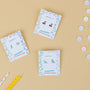 Three pairs of Cherry Enamel Flat Back Kids Earrings are displayed on illustrated cards over a beige background, surrounded by pastel candies and striped candles. These fun hypoallergenic earrings feature cherries, drinks, and shoes.