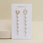 Multi Pearl Drop earrings by JaxKelly: 18k gold plated hoops with dangling chains and small white pearls, displayed on a white JaxKelly card against a light beige background—ideal for elegant pearl drop earring lovers.